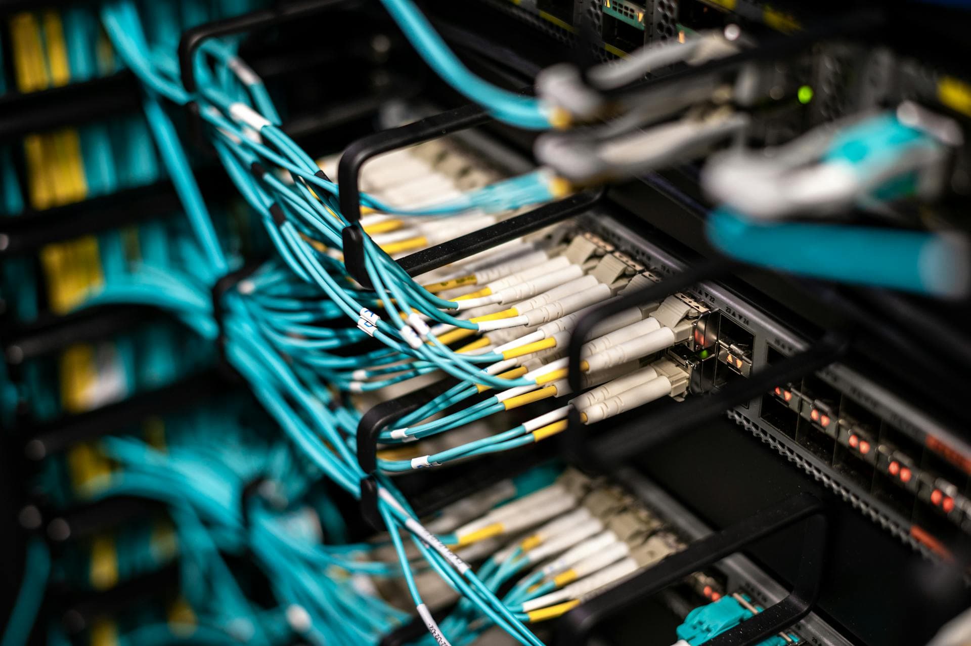 Densely organised optical fibre cables plugged into a data centre patch panel — the physical infrastructure underneath every cloud abstraction, and where workload placement decisions ultimately land.