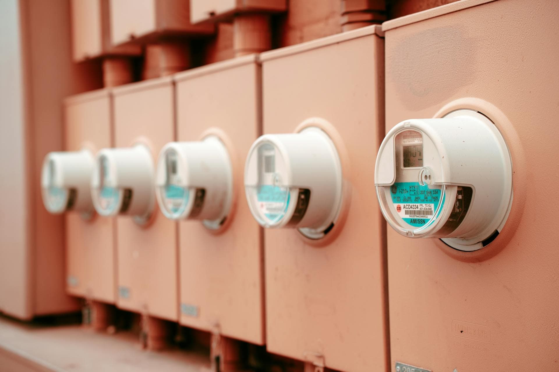 Close-up of a row of industrial electricity meters — evoking the hidden physical-infrastructure costs (power, cooling, UPS) that sit behind every on-prem server invoice but never appear on it.