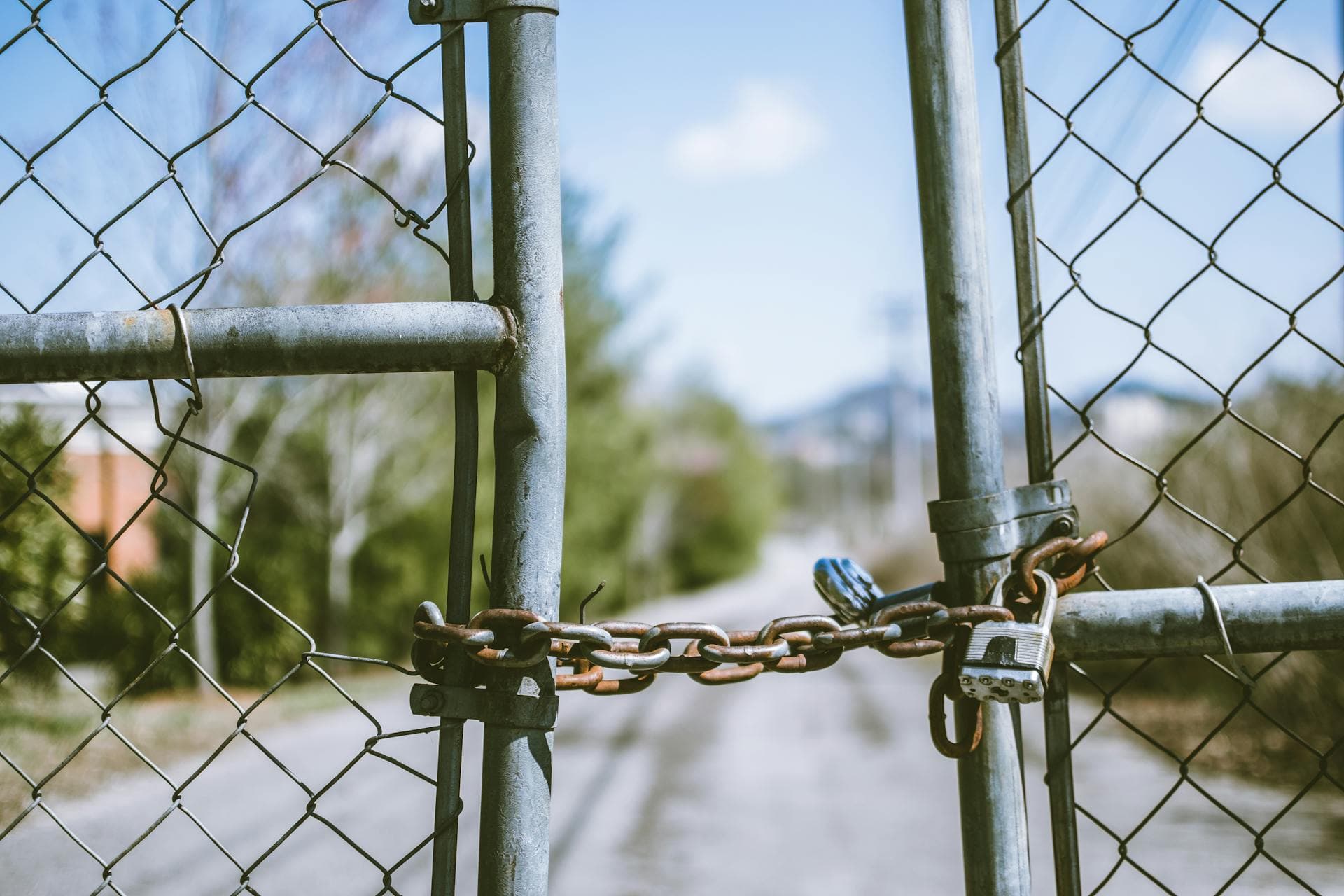 A locked chain securing a steel mesh fence — the visual shape of being shut out of a vendor's customer base, which is what Broadcom's 72-core licensing floor amounts to for an SMB.