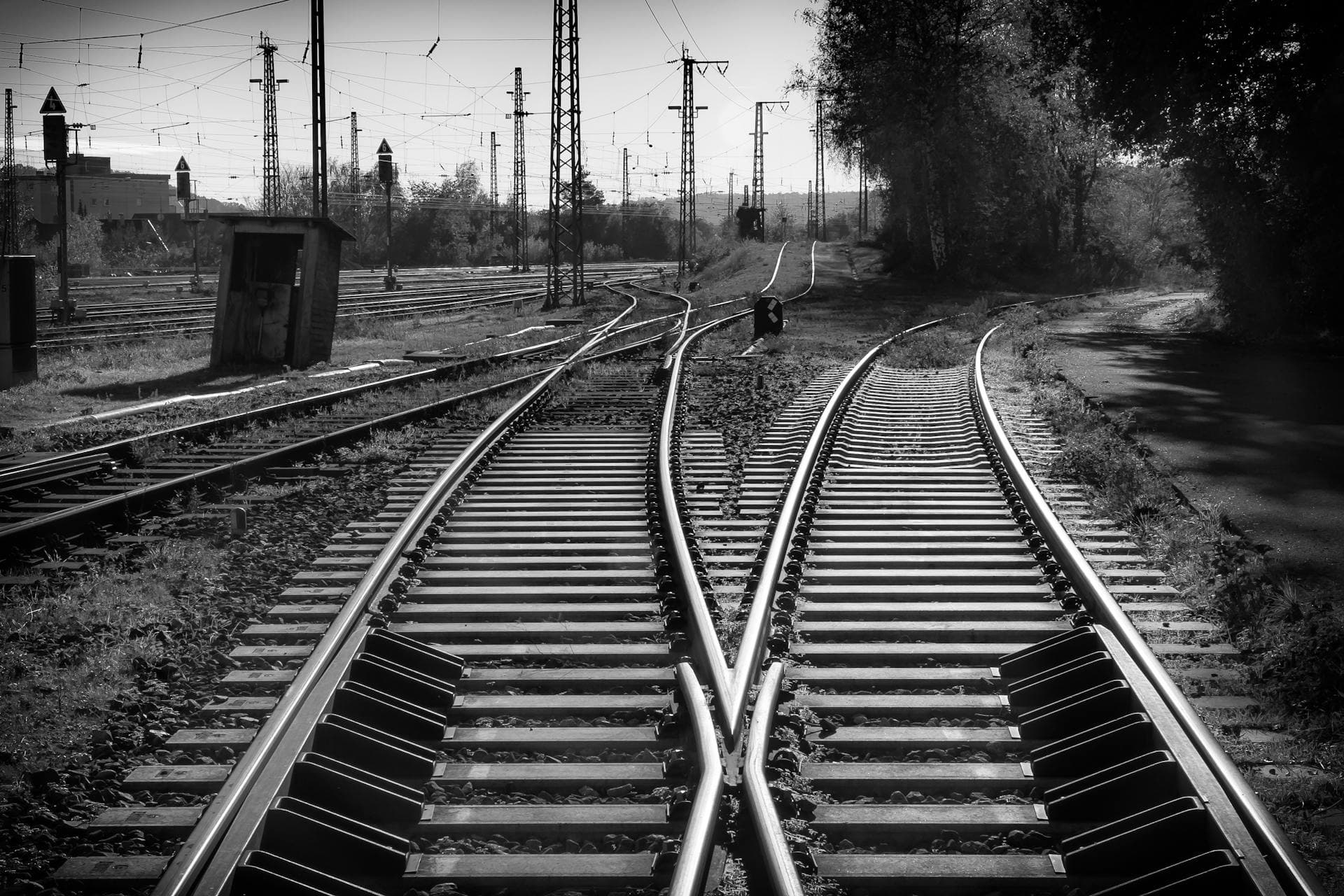 Black-and-white railway tracks converging at a junction — the fork a business reaches when a VMware renewal and a hardware refresh both come due, and has to choose whether to stay on the same line or change tracks.